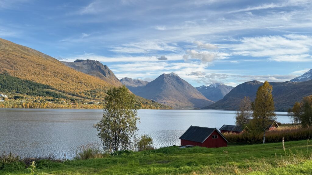 Vuonon rannalla on punaisia rakennuksia ja vuoria taustalla.